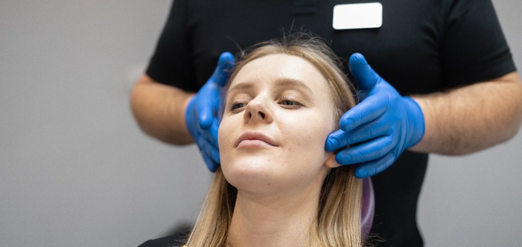 Doctor orthodontist-gnathologist palpates the jaw joints of the female patient