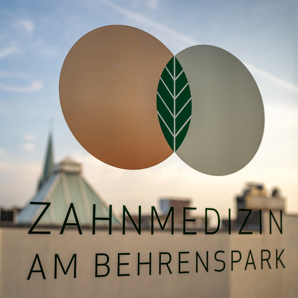 Logo mit zwei überlappenden Kreisen und einem Blatt, Text: "Zahnmedizin am Behrenspark".