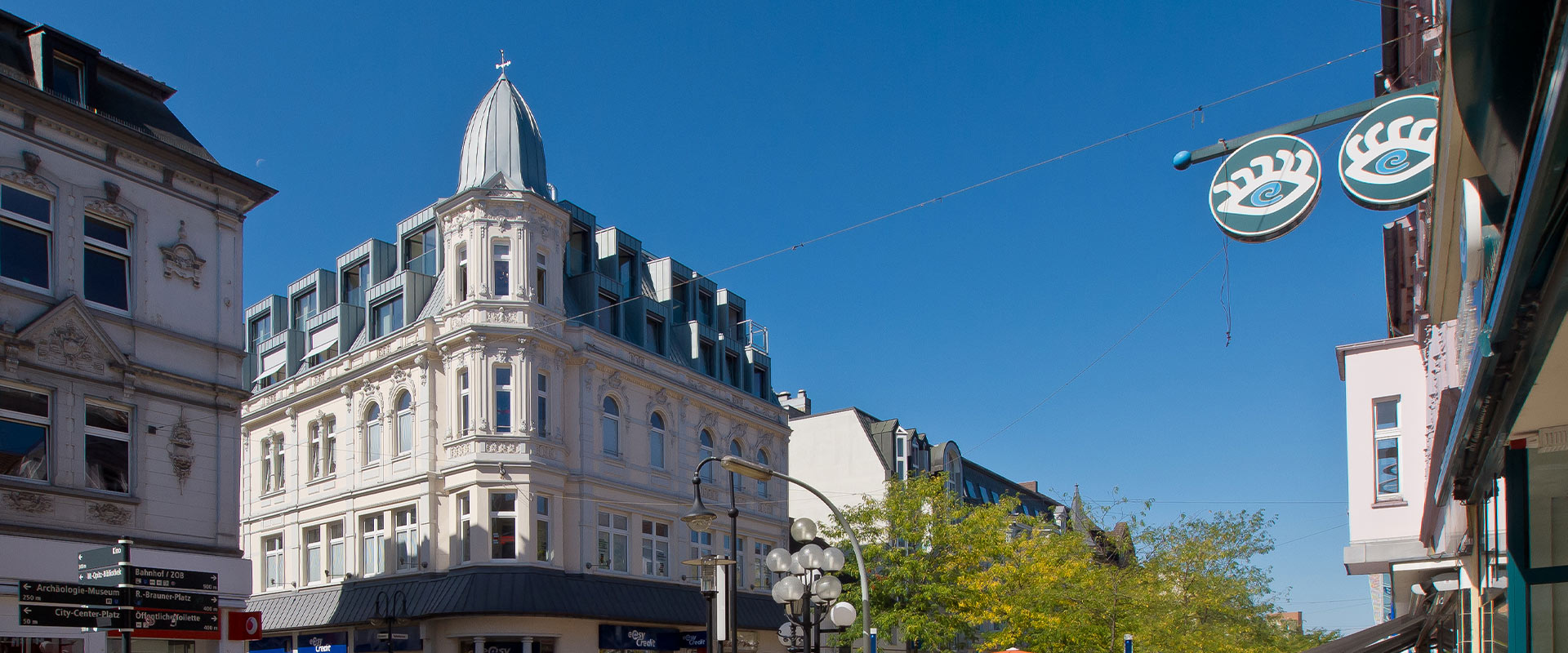 Straßenszene mit historischer Architektur, blauem Himmel und markantem, runden Dach.